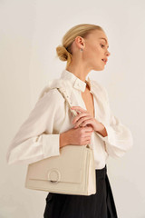 Profile view of model wearing the Oroton Elina Satchel in Milk and Pebble Leather for Women