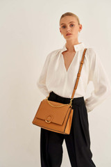 Profile view of model wearing the Oroton Elina Satchel in Tan and Pebble Leather for Women