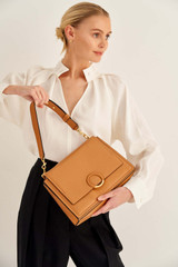 Profile view of model wearing the Oroton Elina Satchel in Tan and Pebble Leather for Women