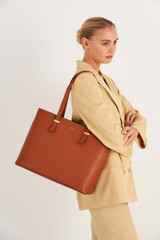 Profile view of model wearing the Oroton Anika 15" Tote & Cover in Cognac and Pebble leather for Women