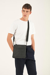 Profile view of model wearing the Oroton Hugo Messenger Bag in Black and Saffiano Leather for Men