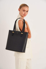 Profile view of model wearing the Oroton Anika Portrait Tote in Black and Pebble leather for Women