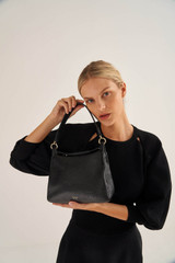 Profile view of model wearing the Oroton Byron Small Hobo in Black and Pebble Leather for Women