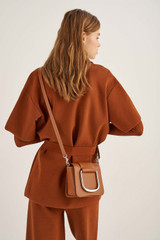 Profile view of model wearing the Oroton Cole Mini Day Bag in Cognac and Smooth Leather for Women