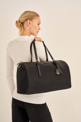 Profile view of model wearing the Oroton Elsie Nylon Gym Tote in Black and Nylon And Pebble Leather for Women