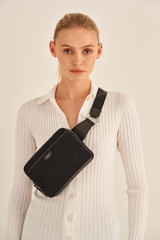 Profile view of model wearing the Oroton Elsie Nylon Waist Bag in Black and Nylon And Pebble Leather for Women