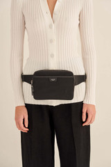 Profile view of model wearing the Oroton Elsie Nylon Waist Bag in Black and Nylon And Pebble Leather for Women