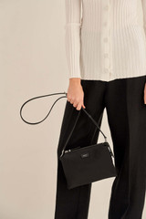 Profile view of model wearing the Oroton Elsie Nylon Zip Top Crossbody in Black and Nylon And Pebble Leather for Women