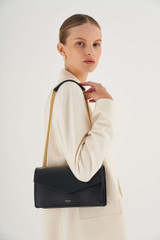 Profile view of model wearing the Oroton Bella Clutch in Black and Soft Saffiano for Women