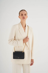 Profile view of model wearing the Oroton Bella Small Clutch in Black and Soft Saffiano for Women