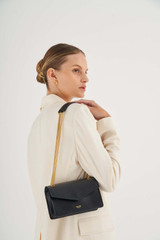 Profile view of model wearing the Oroton Bella Small Clutch in Black and Soft Saffiano for Women