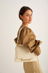 Profile view of model wearing the Oroton Elm Medium Day Bag in French Vanilla and Pebble Leather With Smooth Leather Trim for Women