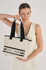 Profile view of model wearing the Oroton Lara Medium Tote in Natural and Recycled Canvas for Women