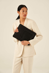 Profile view of model wearing the Oroton Inez Nylon 13" Laptop Cover in Black and Nylon / Saffiano Leather for Women