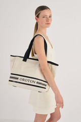 Profile view of model wearing the Oroton Lara Large Tote in Natural and Recycled Canvas for Women