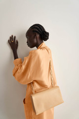 Profile view of model wearing the Oroton Jade Crossbody in Mango and Smooth Leather for Women