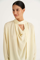 Profile view of model wearing the Oroton Fluid Blouse in Butter and 92% Silk 8% Spandex for Women