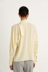 Profile view of model wearing the Oroton Fluid Blouse in Butter and 92% Silk 8% Spandex for Women