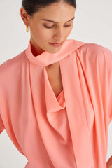 Profile view of model wearing the Oroton Fluid Blouse in Sherbet and 92% Silk 8% Spandex for Women