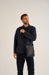 Profile view of model wearing the Oroton Harry Pebble Messenger Bag in Black and Pebble Leather for Men
