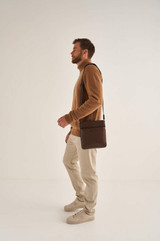 Profile view of model wearing the Oroton Harry Pebble Messenger Bag in Cedar and Pebble Leather for Men