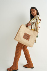 Profile view of model wearing the Oroton Lane Texture Large Tote in Natural/Brandy and Woven Straw and Recycled Smooth Leather Trims for Women