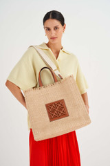 Profile view of model wearing the Oroton Lane Texture Large Tote in Natural/Brandy and Woven Straw and Recycled Smooth Leather Trims for Women