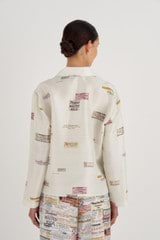Profile view of model wearing the Oroton Long Sleeve Spaced Label Print Camp Shirt in Soft Cream and 100% Silk for Women