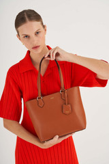 Profile view of model wearing the Oroton Inez Small Shopper Tote in Cognac and Shiny Soft Saffiano for Women