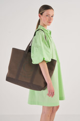 Profile view of model wearing the Oroton Kane Large Shopper Tote in Khaki and Recycled Canvas for Women