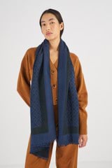 Profile view of model wearing the Oroton Hannah Wrap Scarf in Denim Blue and 40% Acrylic, 33% Viscose, 20% Nylon And 7% Wool for Women