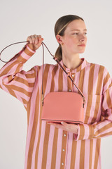 Profile view of model wearing the Oroton Inez Slim Crossbody in Pink Clay and Shiny Soft Saffiano for Women