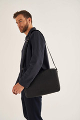 Profile view of model wearing the Oroton Harry Pebble EW Satchel in Black and Pebble Leather for Men
