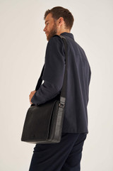 Profile view of model wearing the Oroton Harry Pebble EW Satchel in Black and Pebble Leather for Men