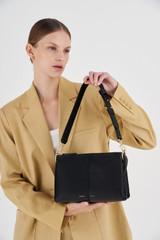 Profile view of model wearing the  Emma Small Day Bag in Black and Pebble Leather for Women