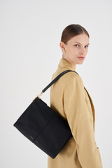 Profile view of model wearing the Oroton Emma Medium Day Bag in Black and Pebble Leather for Women