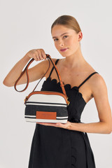 Profile view of model wearing the Oroton Daisy Slim Crossbody in Black/Cream and Stripe Canvas Fabric and Smooth Leather Trim for Women