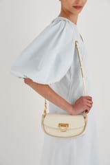 Profile view of model wearing the Oroton Colt Small Baguette in Clotted Cream and Smooth leather for Women