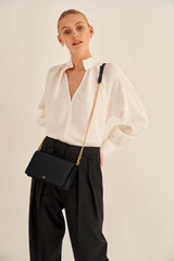 Profile view of model wearing the Oroton Fay Medium Chain Crossbody in Black and Nappa Leather for Women