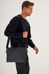 Profile view of model wearing the Oroton Hugo 13" Slim Laptop Bag in Black and Saffiano Leather for Men