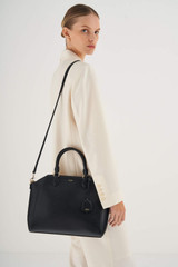 Profile view of model wearing the Oroton Inez Day Bag in Black and Saffiano Leather for Women