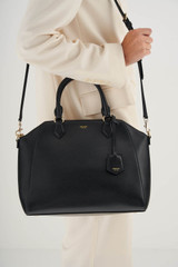 Profile view of model wearing the Oroton Inez Day Bag in Black and Saffiano Leather for Women