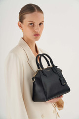 Profile view of model wearing the Oroton Inez Mini Day Bag in Black and Saffiano Leather for Women