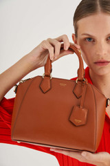 Profile view of model wearing the Oroton Inez Mini Day Bag in Cognac and Shiny Soft Saffiano for Women