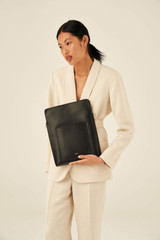 Profile view of model wearing the Oroton Inez 13" Laptop Cover in Black and Shiny Soft Saffiano for Women
