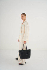 Profile view of model wearing the Oroton Inez Shopper Tote in Black and Shiny Soft Saffiano for Women