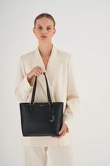 Profile view of model wearing the Oroton Inez Small Shopper Tote in Black and Shiny Soft Saffiano for Women