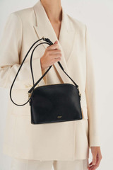Profile view of model wearing the Oroton Inez Slim Crossbody in Black and Shiny Soft Saffiano for Women