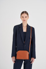 Profile view of model wearing the Oroton Inez Slim Crossbody in Cognac and Shiny Soft Saffiano for Women