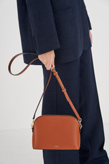 Profile view of model wearing the Oroton Inez Slim Crossbody in Cognac and Shiny Soft Saffiano for Women